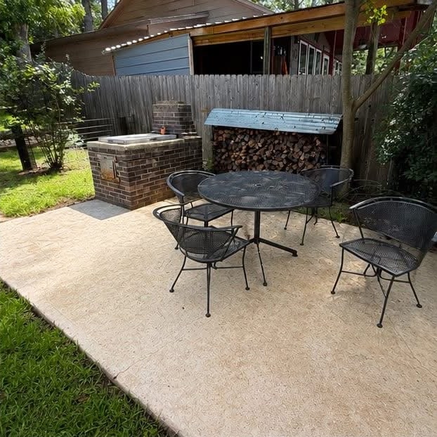 The same concrete patio after cleaning, a pale even surface under the same table and chairs