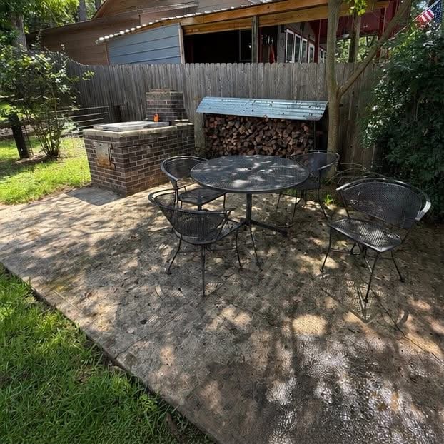 Concrete patio darkened with staining and growth, with a table and chairs on it