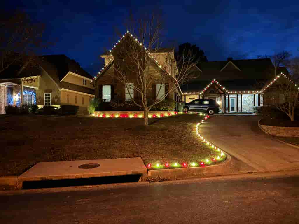Single-story house with warm lights tracing the roof at dusk